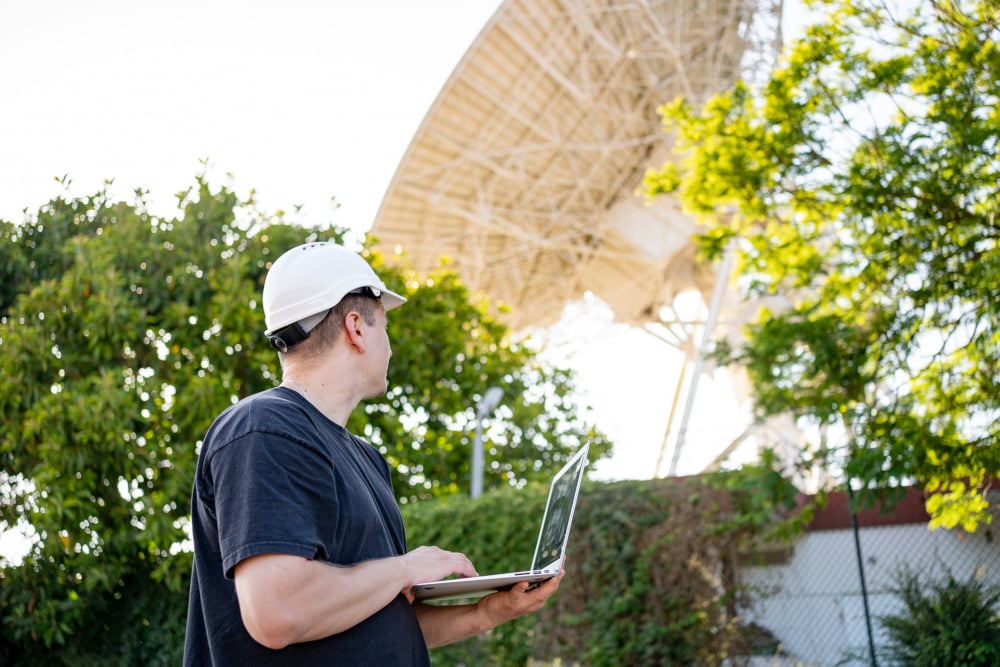 An RF engineer performing spectrum monitoring via a laptop PC while observing a radar system.